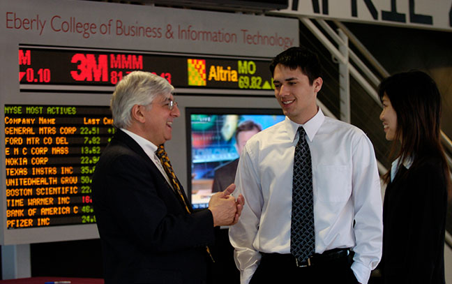 a professor and student stand in front of the stock ticker in Eberlu