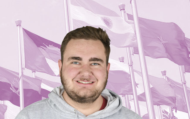 a male student in front of magenta background with international flags