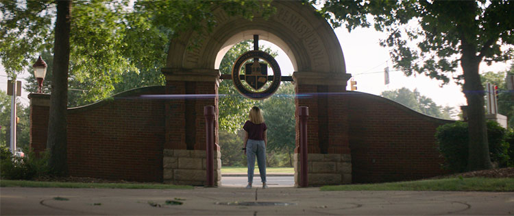 Student standing under an IUP arch