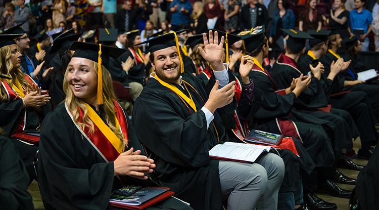 close up of two students waving during the commencement ceremony at the Kovalchick Complex