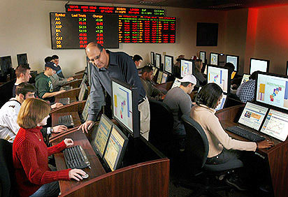A finance professor helps a student in the financial trading lab