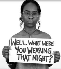 Woman holding sign that reads "Well, what were you wearing that night?"