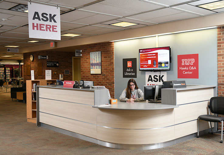 A student worker behind the Information Desk at the IUP Libraries