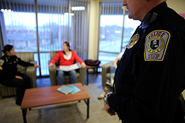 Campus police officer and student talk, while another officer stands in the foreground Campus police officer and student talk, while another officer stands in the foreground