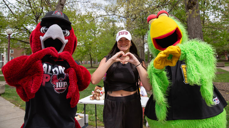 Norm, the Pirates Parrot, and a student make heart signs