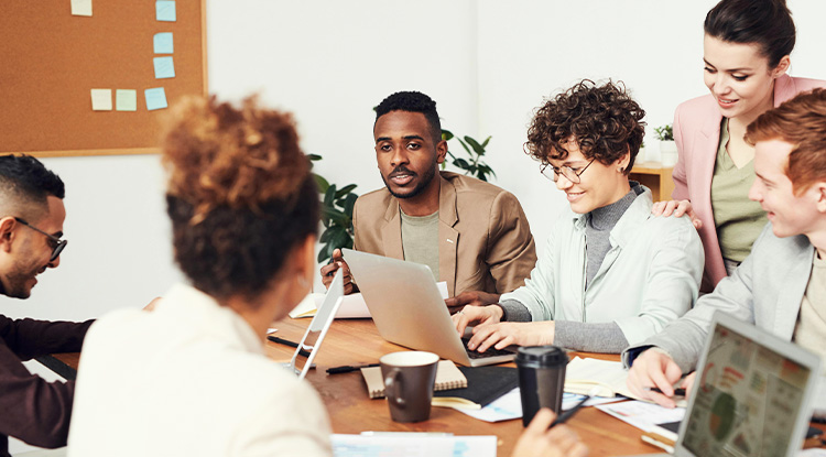 a group of people in a conference room going over various papers and computer screens