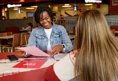 a smiling woman sitting at a desk reviewing papers and folders marked with the IUP logo