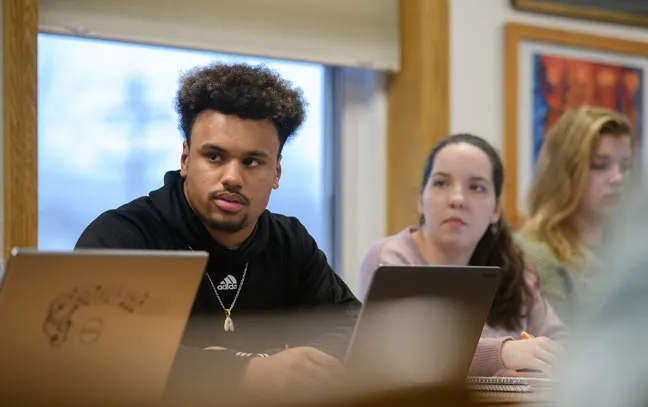 close up of two students sitting with laptops open in class