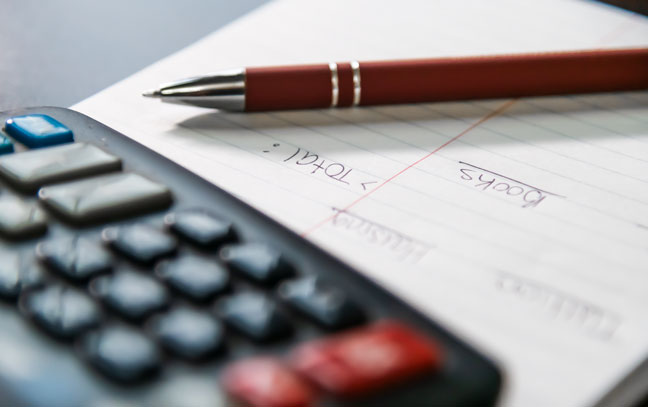 close up of a pen and paper next to a calculator