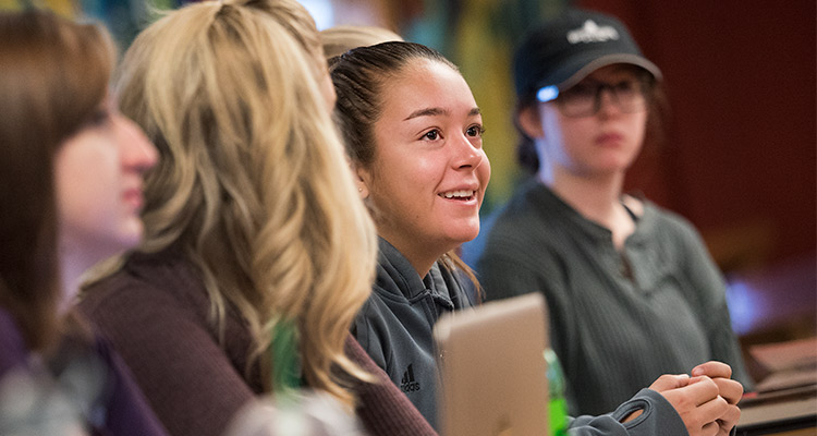 Honors college student smiling in class next to two other students 