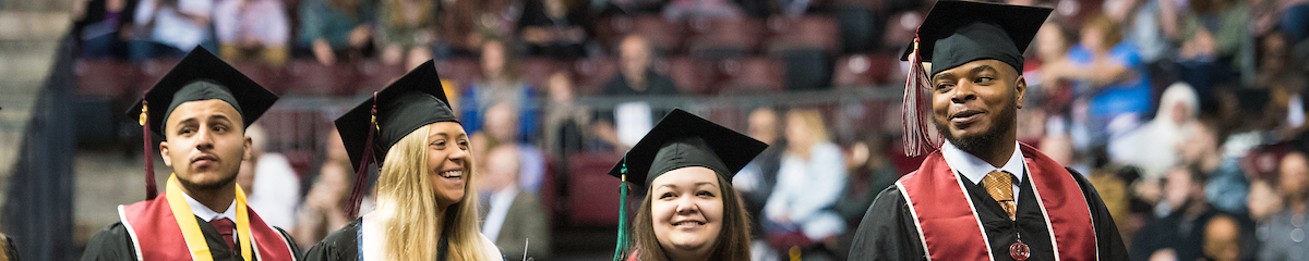 four students in their commencement regalia look in different directions during commencement