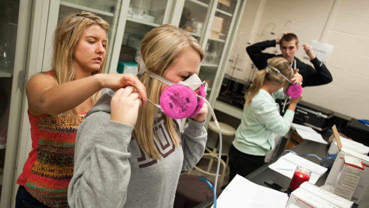 Two safety sciences students try on breathing masks