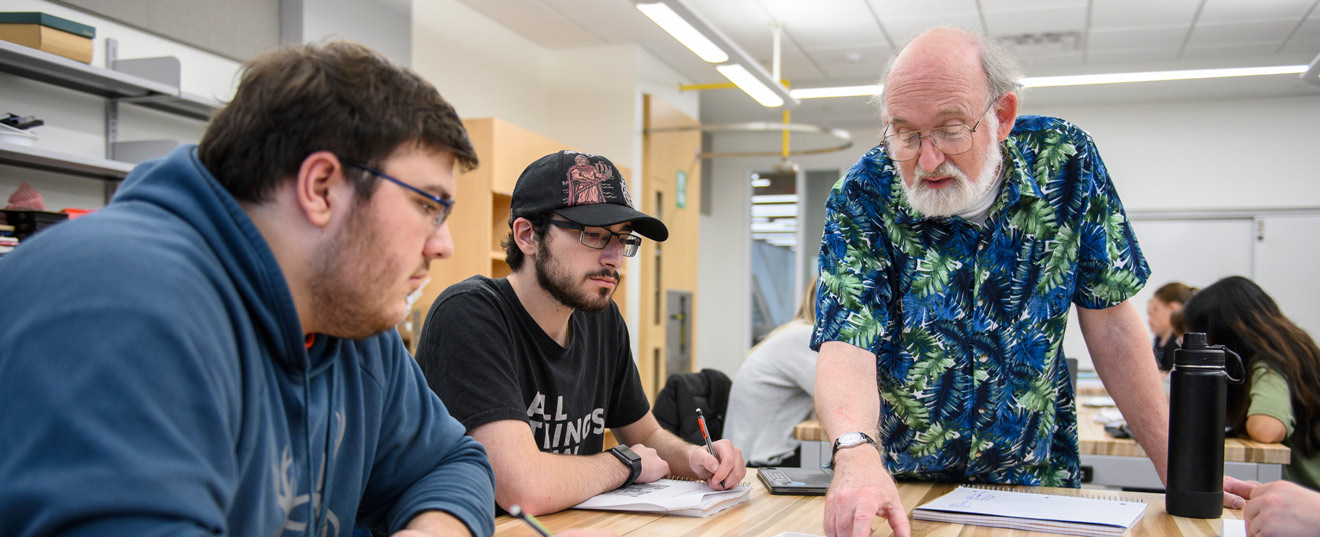 A professor working with two students in a classroom.