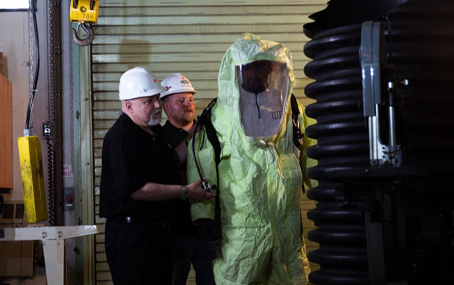 two men help a third get into a safety suit