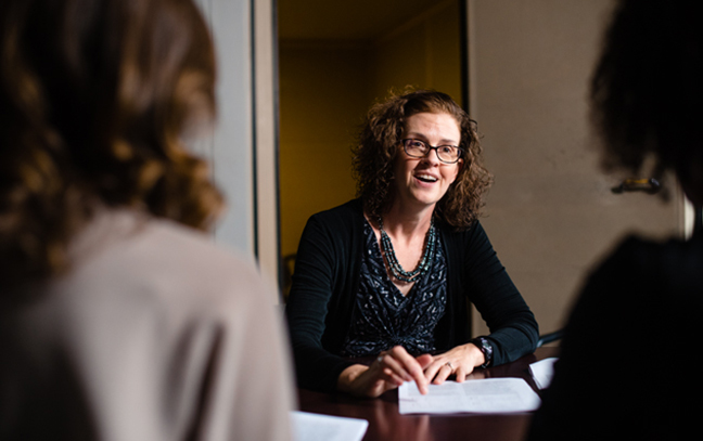 students speaking with a professor in a classroom