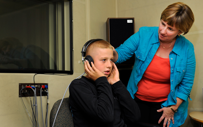 teacher working with a young boy wearing headphones