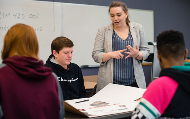 A group of students sitting and standing in a criminology classroom