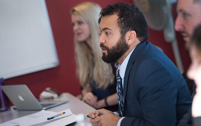 close up of a male student leaning forward engaged in discussion in a class