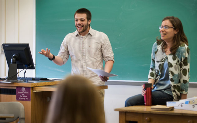 two students present at the front of an English classroom