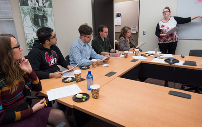 a group of students and a teacher gathered around a table in a classroom
