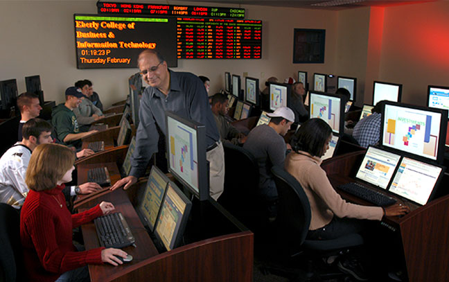 students working on computers in the trading floor room