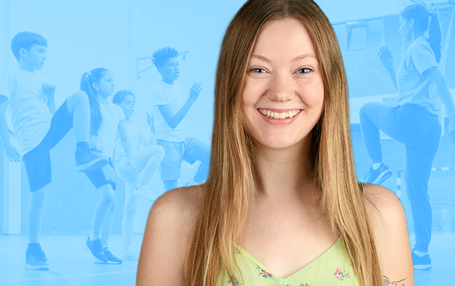 woman smiling with a background of children exercising in a gym