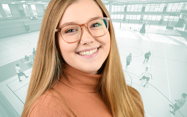 A student being superimposed in front of a muted-teal background showing people playing basketball in a gym.