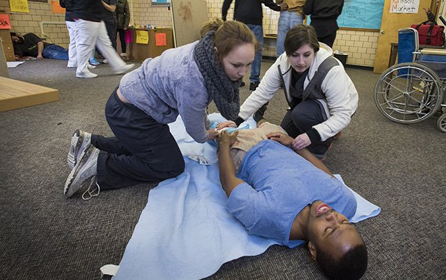 three students practicing paramedic training