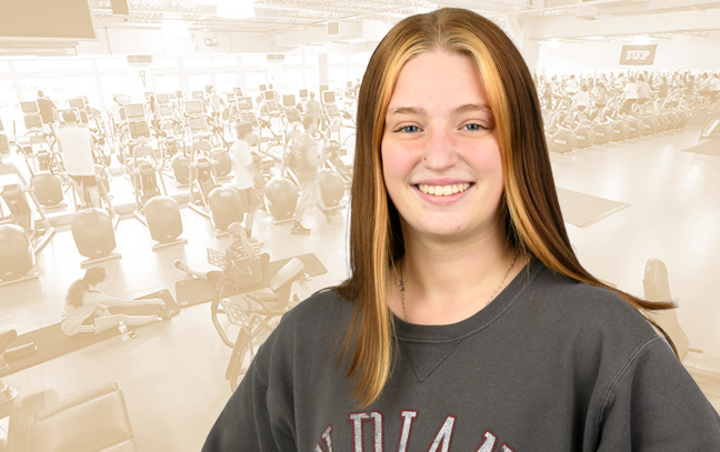 A student being superimposed in front of a muted-orange background showing people exercising in a large gym.