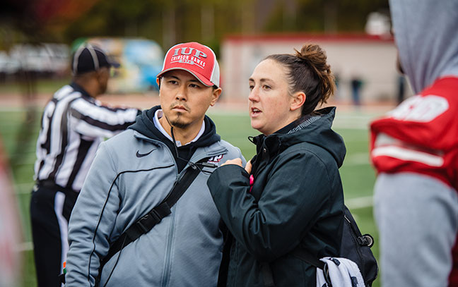 two people talk on the sidelines during a football game
