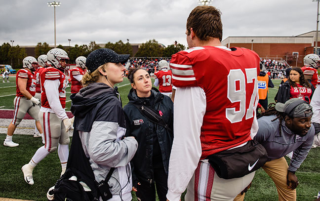 a football player talks to trainers on the field during a game
