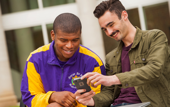 two male students look at something on a phone