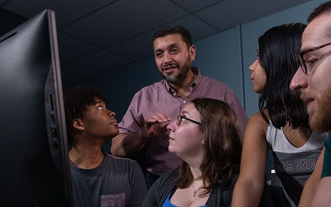 teacher standing near a group of students while lecturing