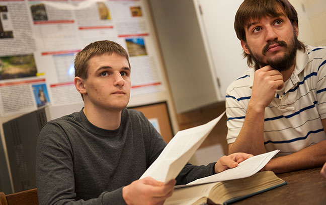 two male students looking up towards the professor in a classroom