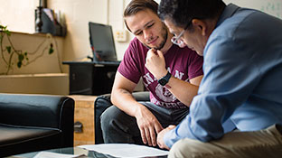 student and professor seated together talking