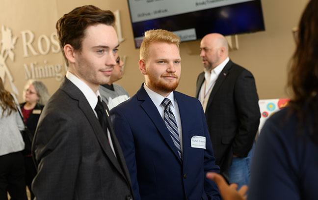 two students talking to a professional at an event