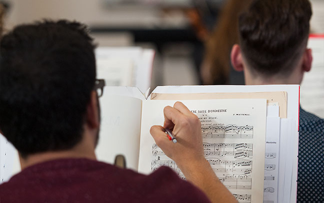 close up of someone writing on sheet music