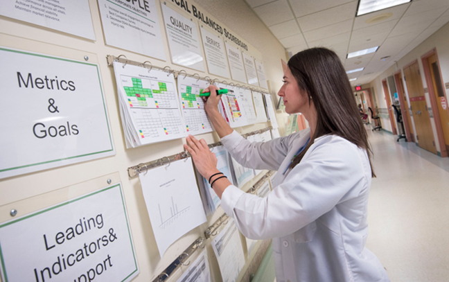 a female nursing student writing on a board on a wall