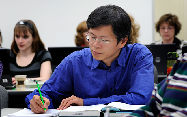 close up of a male student taking notes in a classroom