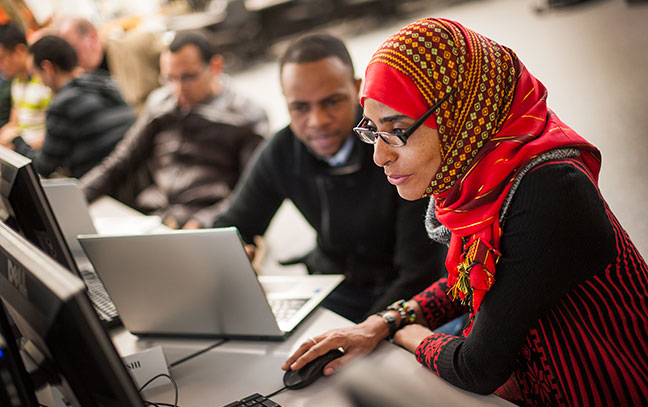 two students look at a computer screen together in a classroom