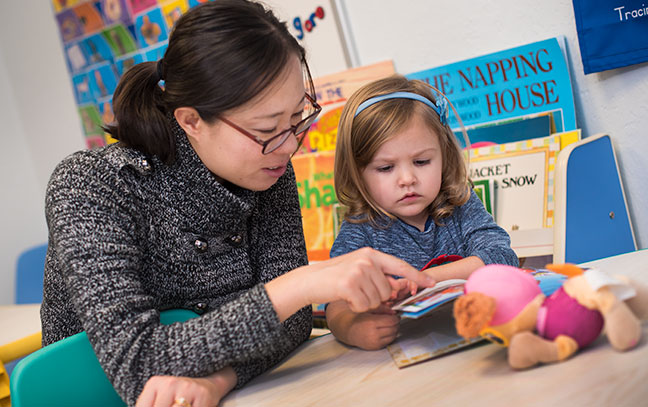 a female student works with a small child in a child care setting