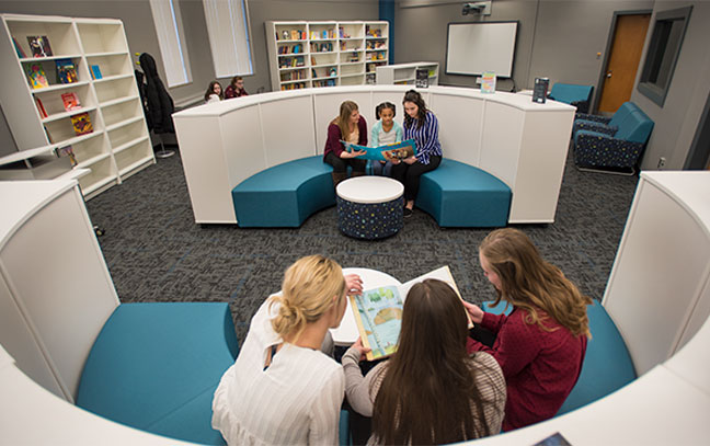 groups of students and student teachers in the literacy center reading books