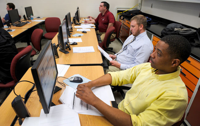 A group of students lined up at a long table on computers