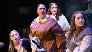 a group of female students on stage during a production of Little Women
