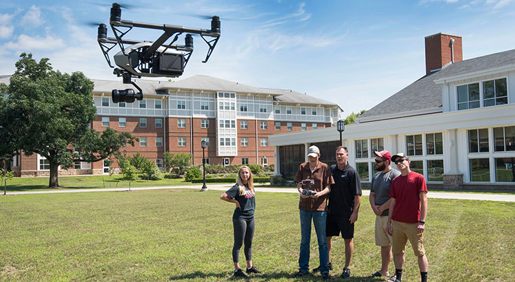 Students and Professor Benhart flying a photography drone in North Lawn