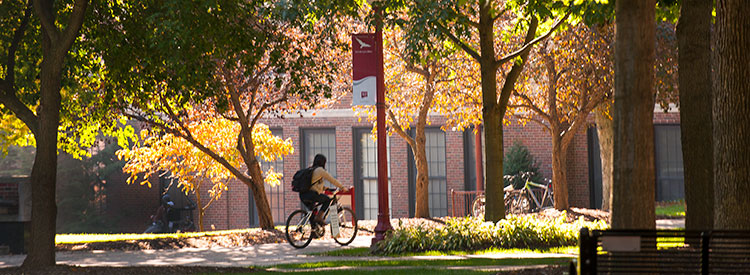 A student cycles through the IUP Oak Grove 
