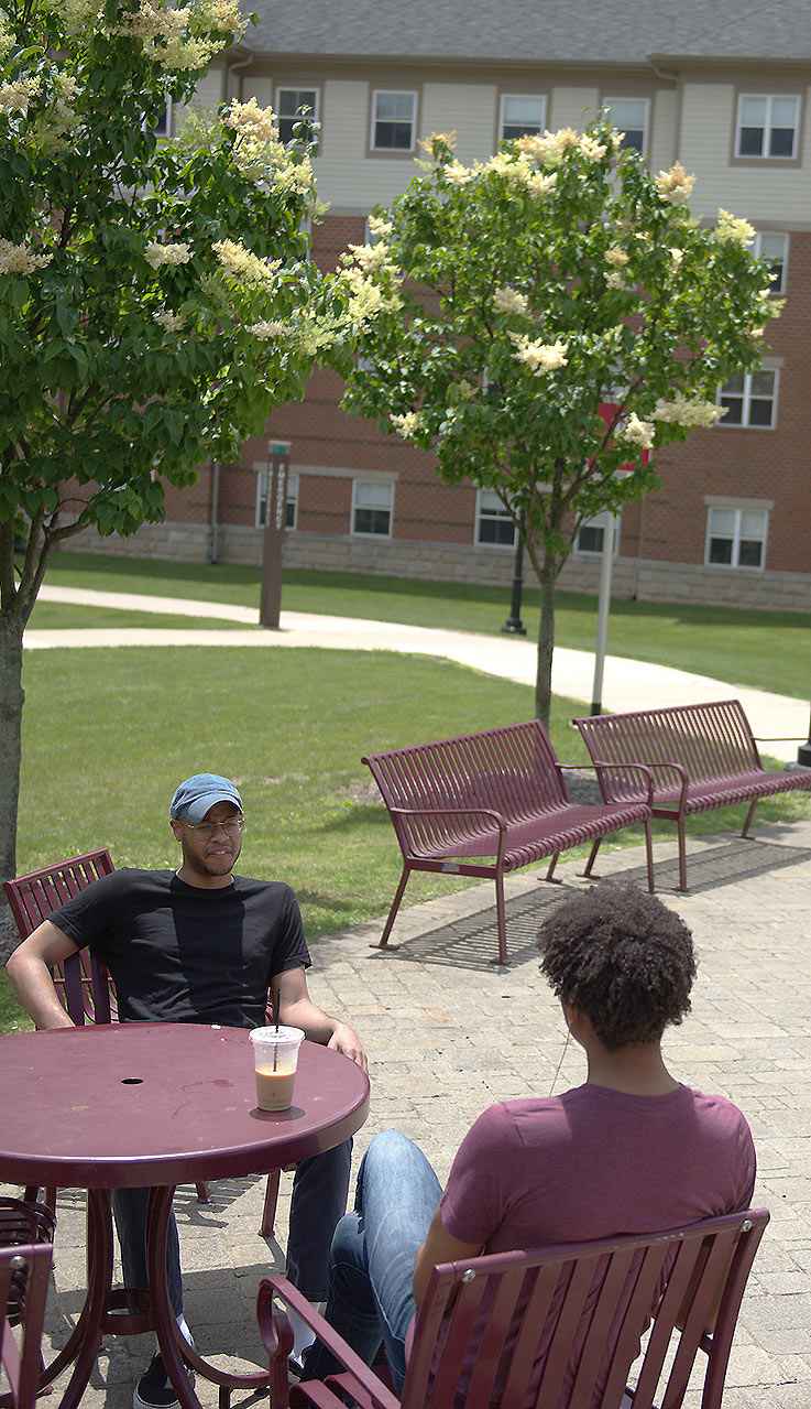 Two African American students talking at a table in the Delaney courtyard