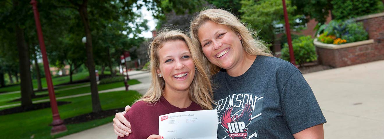 A mother and daughter hug in the Oak Grove as they celebrate the daughter's acceptance into IUP