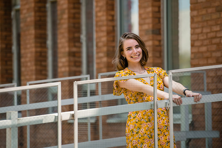 Amelia smiles on the walkway outside of Ackerman Hall.