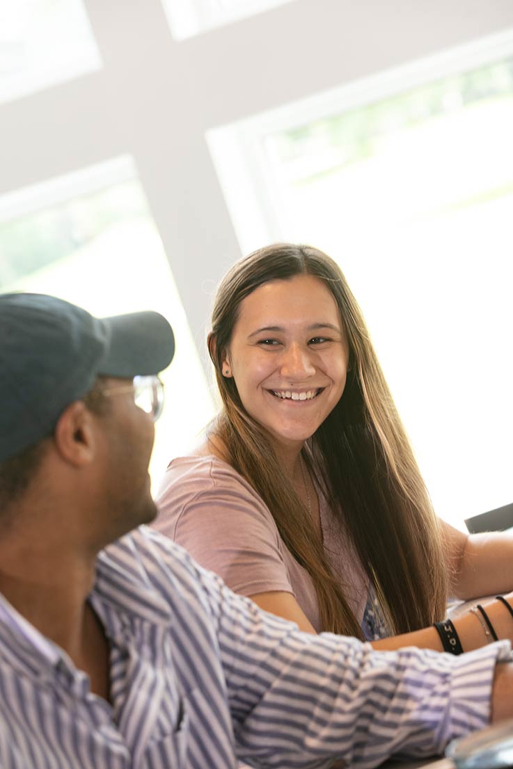 Two students looking at each other and smiling